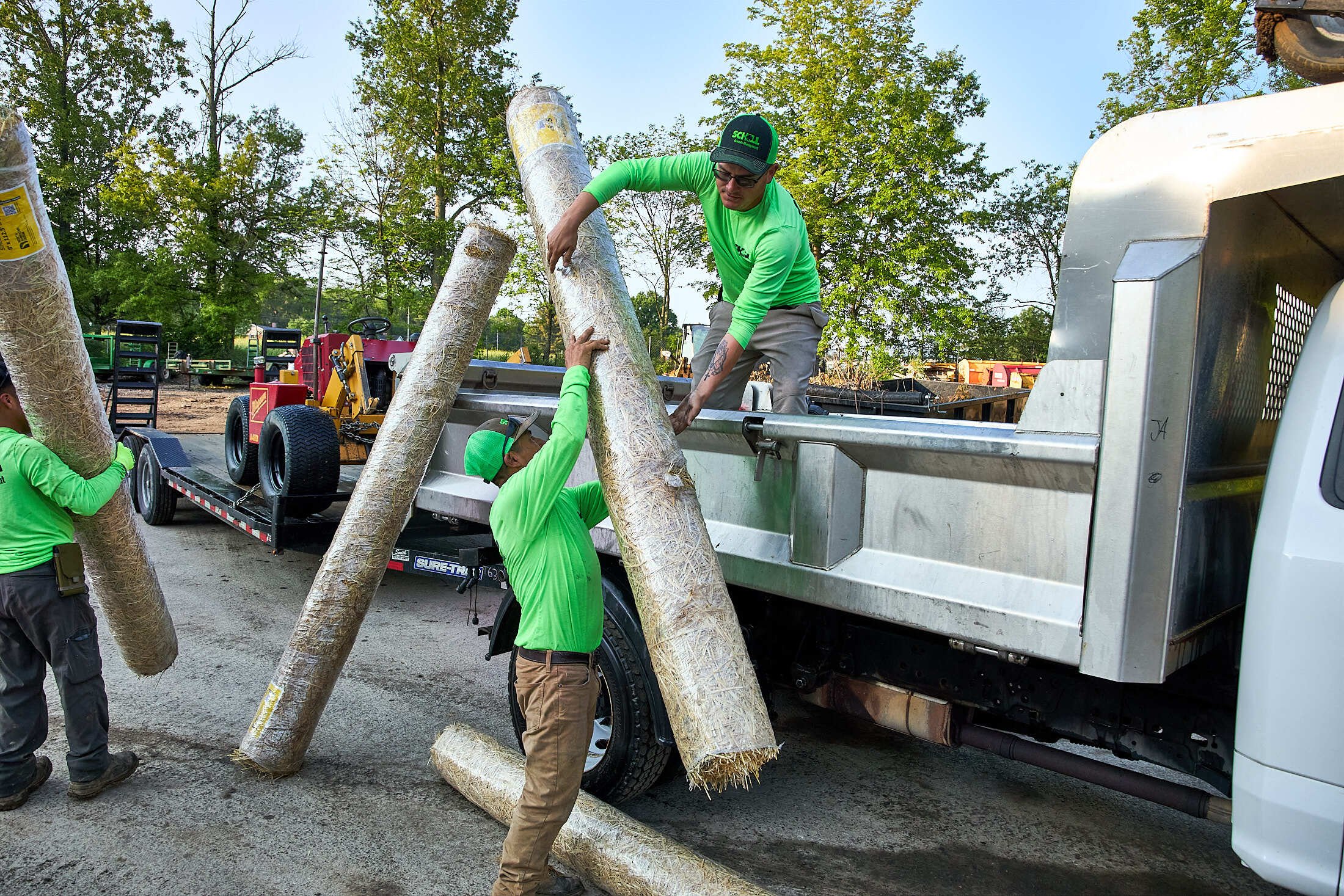 Landscape construction crew loading rolls of hay in truck