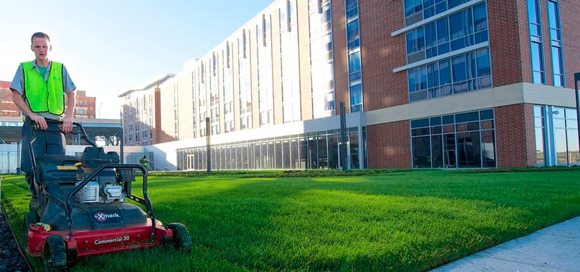 landscaper mowing lawn in front of a commercial building