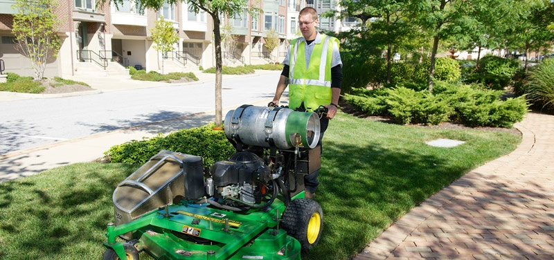 commercial landscaper mowing lawn near driveway at a commercial property